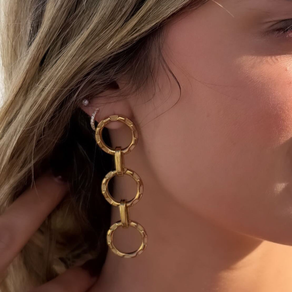 Close-up of a woman wearing gold hoop earrings with a blurred background