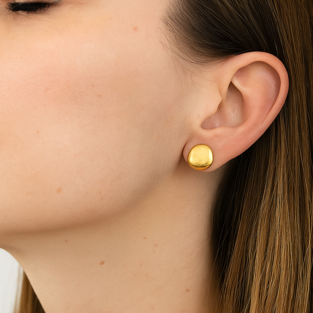 Close-up of a person wearing gold stud earrings.