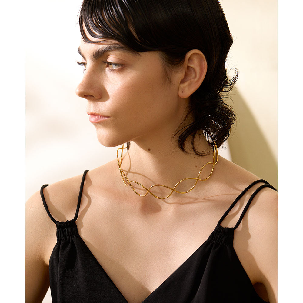 Woman wearing a gold necklace against a neutral background